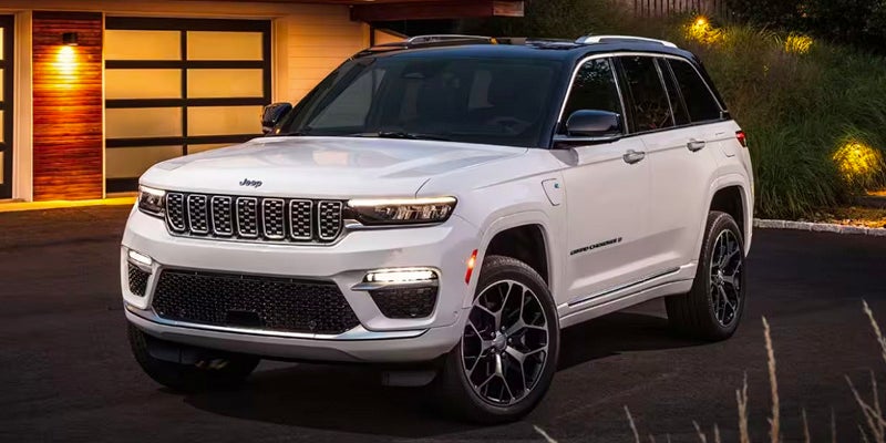 View of a white 2024 Jeep Grand Cherokee pared in a driveway at night time