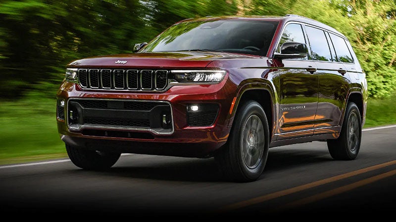 Red 2023 Jeep Grand Cherokee driving down road